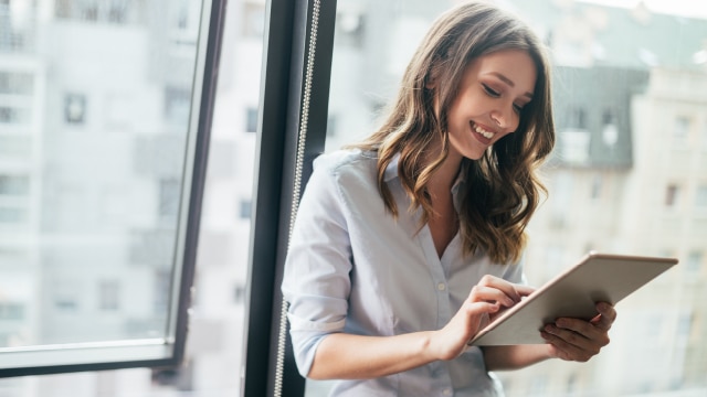 Woman smiling while looking at electronic tablet